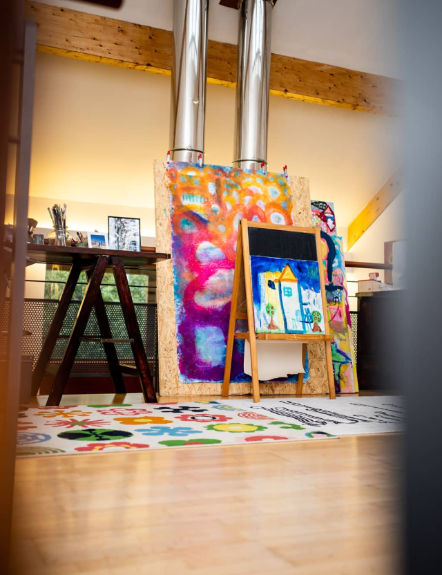 Louise's studio with easels holding colourful canvases, a patterned rug and a work table