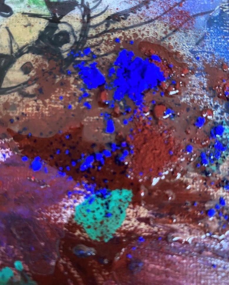 Close-up of blue and earth pigments sprinkled onto a wet canvas