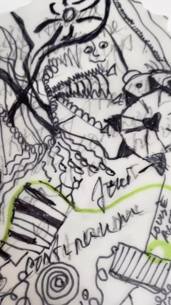 Close-up of an ink drawing filled with abstract faces, patterns and handwritten words, with a single lime-green line