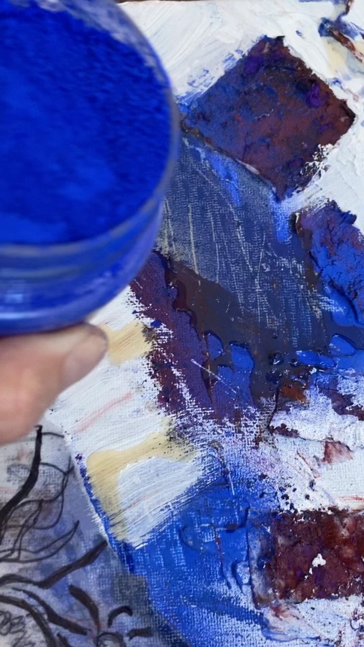 Louise holding blue powder pigment over a painted surface